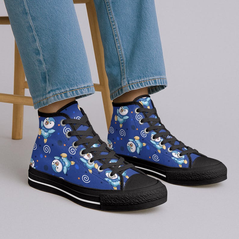 May include: Blue high-top sneakers with a repeating pattern of cartoon penguins and swirls. The sneakers have black soles, black laces, and a white stripe along the bottom of the sole.