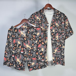 May include: A short-sleeve button-down shirt and matching shorts set featuring an all-over print of grey dragon-like creatures, orange flames, and red and white spheres on a dark background, displayed over a plain white t-shirt.