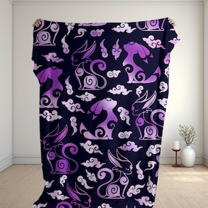 May include: A dark purple and black blanket featuring a repeating pattern of stylized, silhouette-style creatures with long ears and curled tails, interspersed with small, swirling cloud shapes throughout the entire fabric surface.
