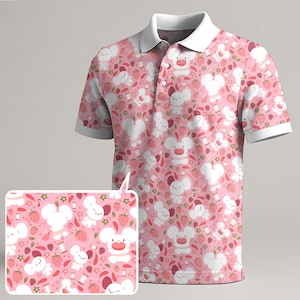 Könnte beinhalten: Rosa Polo-Shirt mit weißem Kragen und Manschetten. Das Shirt zeigt ein sich wiederholendes Muster aus weißen Cartoon-Mäusen, Erdbeeren, Blumen und Nähgarnrollen. Das Design wird auf dem Shirt und einem kleineren inset-Bild angezeigt.