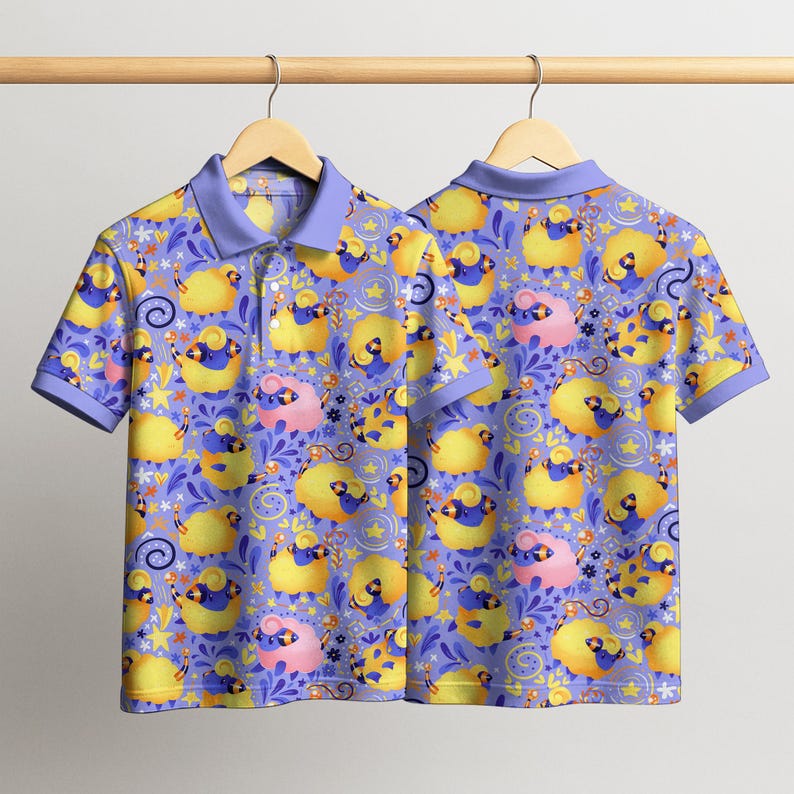 May include: A short-sleeved polo shirt with a whimsical pattern of yellow and pink sheep on a periwinkle background. The shirt has a light purple collar and sleeve cuffs. The sheep are interspersed with stars and floral elements.