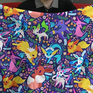 May include: A soft fleece blanket featuring a dark purple background with a repeating pattern of various colorful cartoon creatures and stylized floral elements in shades of yellow, pink, blue, green, and white across the entire fabric surface.