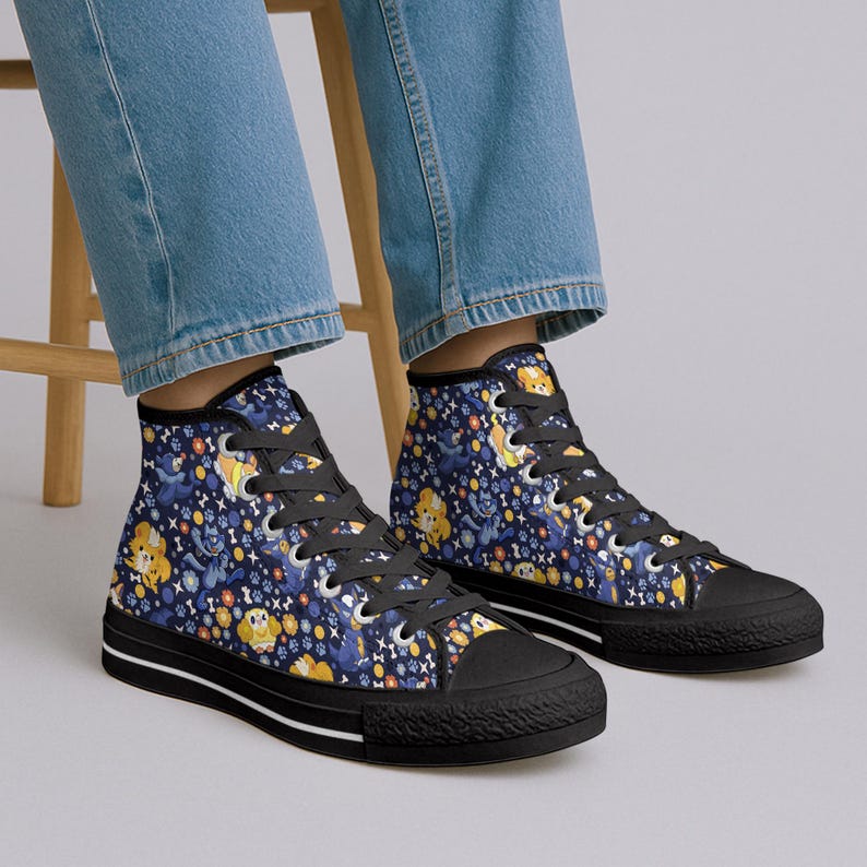 May include: High-top canvas sneakers with a black sole and a navy blue upper. The upper is patterned with cartoon dogs, bones, and stars in yellow, blue, and white. The sneakers have black laces and a white stripe on the sole.