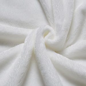 May include: A solid white fabric with a soft, plush, and fuzzy texture. The material is gathered in the center, creating deep, flowing folds and shadows that highlight the dense, velvety pile of the textile surface across the entire frame.