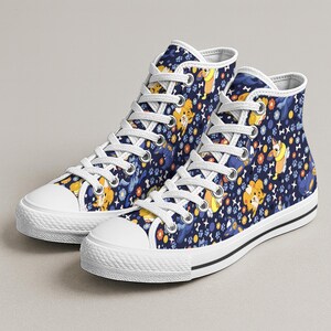 May include: High-top canvas sneakers with a navy blue background featuring a repeating pattern of cartoon dogs, paw prints, and flowers in yellow, orange, and blue. The sneakers have white laces, a white toe cap, and a black stripe on the sole.