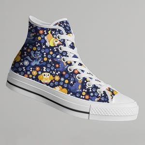 May include: High-top canvas sneaker with a navy blue background and a repeating pattern of cartoon dogs, flowers, and paw prints. The shoe has white laces, a white rubber sole, and a white toe cap.