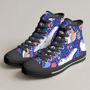 May include: High-top canvas sneakers with a vibrant underwater-themed pattern. The design features cartoon sharks, coral, starfish, and other sea life on a dark blue background. The shoes have black laces, soles, and toe caps.