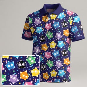 Può includere: Una polo blu navy con un motivo ripetuto di personaggi a forma di stella dei cartoni animati colorati. Il design include stelle, comete e vari personaggi colorati con facce sorridenti. La camicia ha un colletto e polsini blu scuro.