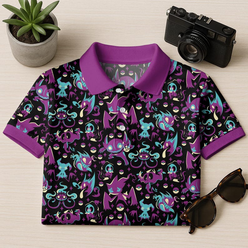 May include: Black polo shirt with a purple collar and cuffs. The shirt features a repeating pattern of purple, teal, and white cartoon characters on a black background. A pair of sunglasses and a camera are next to the shirt.