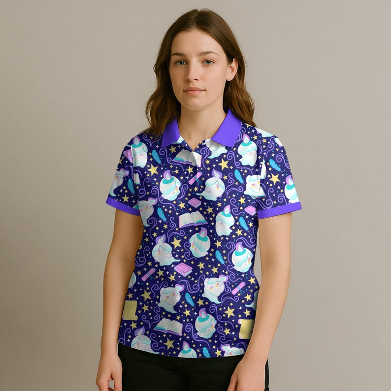 May include: A dark blue polo shirt with a whimsical pattern of white figures, books, feathers, and stars. The shirt has a purple collar and sleeve trim. The overall design is playful and fantasy-themed.