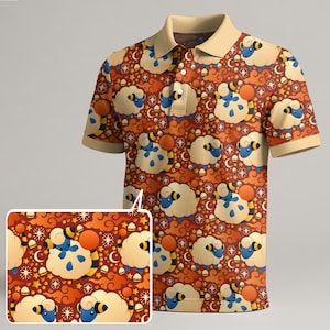 May include: A short-sleeved polo shirt featuring a repeating pattern of cartoon sheep, moons, and stars on a reddish-brown backdrop. The collar and sleeve cuffs are a light tan colour. The shirt has a three-button placket.