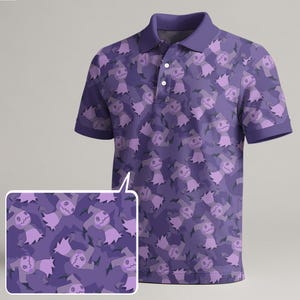 May include: A purple polo shirt featuring a repeating pattern of cartoon characters in shades of purple and lavender. The shirt has a collar, short sleeves, and a three-button placket. A close-up of the pattern is shown.