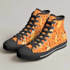 May include: High-top sneakers with a vibrant orange pattern featuring cartoon characters, hearts, and stars. The shoes have black laces, toe caps, and soles, with a white stripe along the sole.