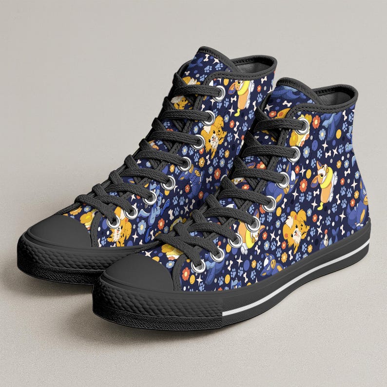 May include: High-top canvas sneakers with a navy blue background and a repeating pattern of cartoon dogs, paw prints, and flowers in yellow, orange, and blue. The sneakers have black laces, black rubber soles, and a white stripe.