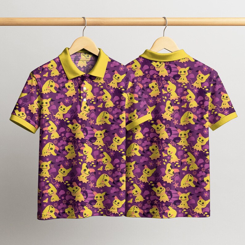 May include: A short-sleeved polo shirt featuring a repeating pattern of yellow cartoon characters on a purple background. The shirt has a yellow collar and sleeve trim. The shirt is hanging on a wooden hanger.