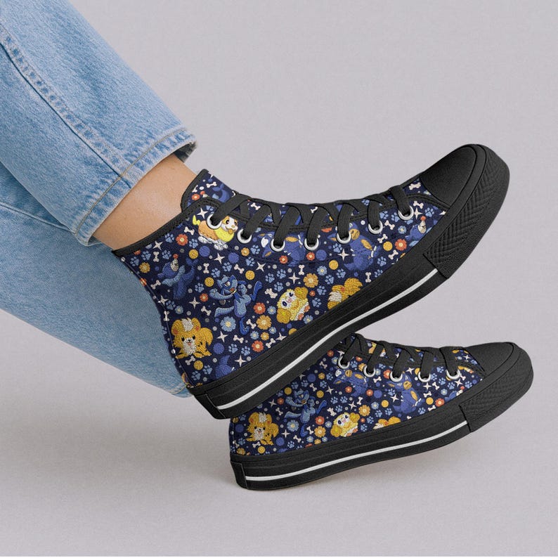 May include: High-top canvas sneakers with a navy blue background and a repeating pattern of cartoon dogs, flowers, and bones. The sneakers have black soles, black laces, and a white stripe along the sole.