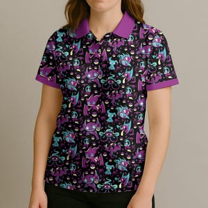 May include: Black polo shirt with a repeating pattern of purple and teal cartoon characters. The shirt has a purple collar and sleeve trim. The design features various creatures on a black background.