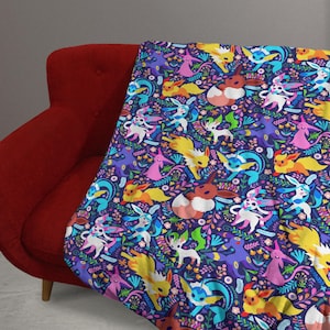 May include: A soft throw blanket featuring a dark purple background with a repeating pattern of various colorful cartoon creatures, including yellow, blue, pink, and brown characters interspersed with green leaves and small flowers.