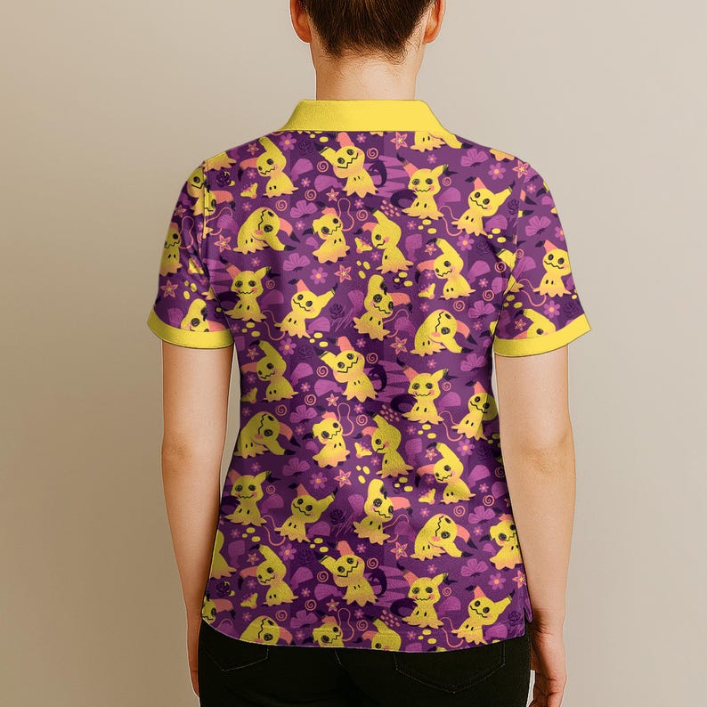 May include: Purple polo shirt featuring a repeating pattern of yellow cartoon characters. The shirt has a yellow collar and sleeve trim. The design includes yellow cartoon characters, flowers, and clouds on a purple background.