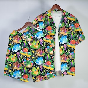 May include: A matching set of colorful, patterned clothing, including a short-sleeved button-down shirt and shorts. The black background is covered with a whimsical design of mushrooms, mountains, and cartoon characters in various colors. The shirt is open, revealing a white undershirt.