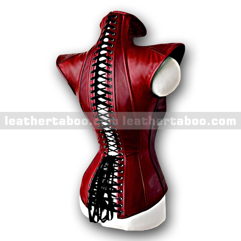 Pu&ograve; includere: Un corsetto in pelle bordeaux con lacci neri sulla schiena. Il corsetto ha un colletto alto e spalle strutturate. Il testo "leathertaboo.com" &egrave; stampato in basso a sinistra e a destra dell'immagine.