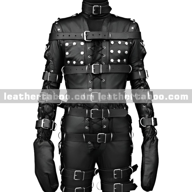 May include: Black leather restraint suit with multiple straps, buckles, and studded accents. The suit features a high collar, long sleeves with attached mittens, and a series of straps across the chest, arms, and legs. The suit is designed for restraint purposes.