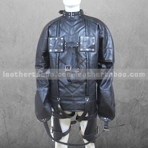 May include: Black leather restraint jacket with straps and buckles. The jacket has long sleeves with straps at the wrists. The jacket is worn on a mannequin.