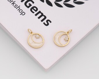 May include: Two gold-colored pendants, each featuring a crescent moon design with a white enamel inlay and a small, sparkling star. The pendants are round with a loop at the top for a chain. The background is a white surface with the text "enGems Workshop".
