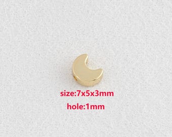 Puede incluir: Una cuenta dorada en forma de media luna. El texto en la imagen indica que la cuenta mide 7x5x3mm con un agujero de 1mm. La cuenta está sobre un fondo blanco.
