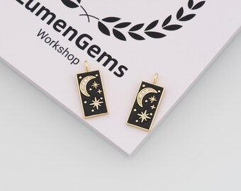May include: Two black rectangular pendants with gold trim, each featuring a crescent moon and stars design. The moon is embellished with small, clear stones. The pendants are from the LumenGems Workshop.