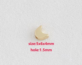 Puede incluir: Una cuenta dorada en forma de media luna. La cuenta mide 5 mm x 6 mm x 4 mm con un agujero de 1,5 mm. La cuenta está sobre una superficie blanca texturizada. El texto "size:5x6x4mm" y "hole:1.5mm" es rojo.