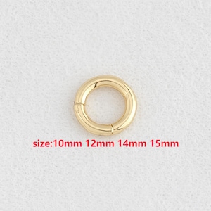 May include: A gold-colored, round clasp with a hinged opening. The clasp is shown against a white background. Text in red indicates available sizes: 10mm, 12mm, 14mm, and 15mm.