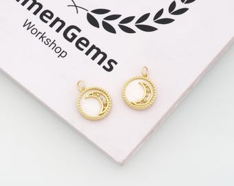 May include: Two circular gold-toned pendants featuring a crescent moon cutout design with small star accents. Each pendant has a white inlay and a beaded outer edge, with a small jump ring at the top for attachment. The text LumenGems Workshop is visible.