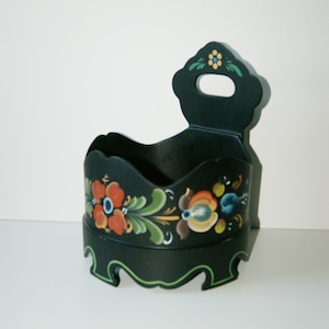 May include: Black wooden box with a handle and a decorative floral design painted in red, green, blue, and yellow. The box has a scalloped edge.
