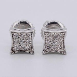 May include: A pair of silver-toned stud earrings featuring a square, concave shape with curved sides. Each earring is set with nine small, clear, round-cut stones arranged in a grid pattern, held within a polished metal frame with a post backing.