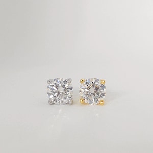 May include: Two round-cut diamond stud earrings. One earring has a silver setting, and the other has a gold setting. The diamonds are clear and sparkling, set with four prongs.