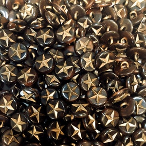 May include: A close-up of a pile of brown and gold star-shaped buttons. The buttons are all the same size and shape, and they are arranged in a random pattern.