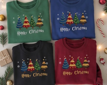 Op de afbeelding: Vier crewneck sweatshirts in groen, blauw, zwart en bordeauxrood, elk geborduurd met een rij kerstbomen en de woorden "Happy Christmas". De sweatshirts worden omringd door kerstversieringen.
