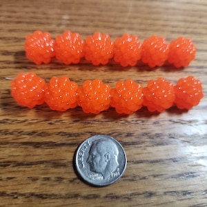 May include: Two rows of bright orange, round, textured beads. The beads are about the size of a dime.
