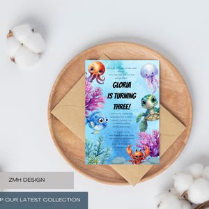 Pode incluir: Um convite de aniversário com tema subaquático. O convite apresenta ilustrações coloridas de criaturas marinhas como um polvo, uma tartaruga e um caranguejo. O texto diz "Gloria está fazendo três anos!" em um fundo azul.