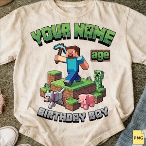 May include: A beige t-shirt featuring a graphic print with the text "YOUR NAME" at the top and "BIRTHDAY BOY" at the bottom. The center shows a pixelated character holding a pickaxe, a green creeper, a grey wolf, and a pink pig on grass blocks.