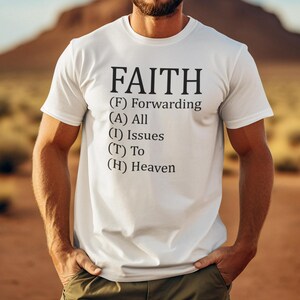 Puede incluir: Camiseta blanca con la palabra "FAITH" en negro. Debajo, la definición del acrónimo: Forwarding All Issues To Heaven. La camiseta de manga corta la lleva una persona.