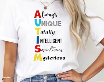 May include: White t-shirt with the word "AUTISM" spelled vertically in colorful letters. Each letter of the word is followed by a descriptive word: Always, Unique, Totally, Intelligent, Sometimes, Mysterious.