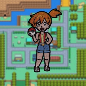 May include: An embroidered patch featuring a cartoon character with orange hair, wearing a red and yellow tank top, blue shorts, and holding a red and white Pokeball. The character is standing on a green and blue background.