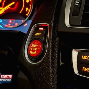 May include: Close-up of a car's interior, highlighting the dashboard and controls. A red "Start Stop Engine" button is prominently displayed, along with an "Off" button. The dashboard gauges are illuminated, and the "Mode" and "FM/AM" buttons are visible.