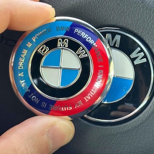 Puede incluir: Un emblema redondo de BMW con un esquema de color azul, rojo y blanco. El emblema presenta el logotipo de BMW y el texto "BMW Power Performance" y "Just a dream M Power".