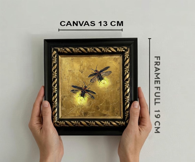 May include: A square painting of two fireflies with glowing yellow abdomens on a textured gold background, encased in a black and gold ornate frame. The canvas measures 13 cm, and the full frame measures 19 cm as indicated by the text labels.