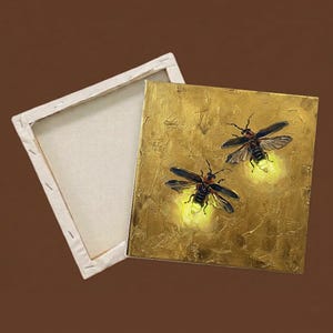 May include: A square canvas painting featuring two fireflies with glowing yellow abdomens against a textured metallic gold background, shown alongside an empty wooden stretcher frame with a plain white canvas back.