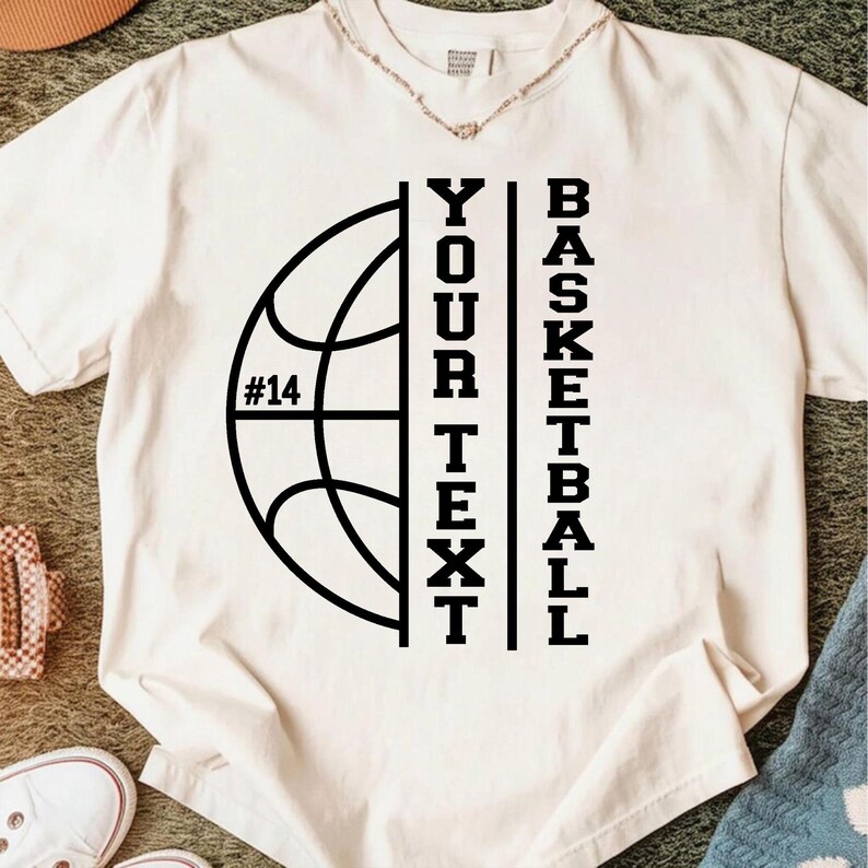 Peut inclure: T-shirt cr&egrave;me avec un graphisme de basket-ball noir. Le motif comprend un ballon de basket, le num&eacute;ro 14 et les mots "YOUR TEXT" et "BASKETBALL" en texte vertical. Le t-shirt est en mati&egrave;re souple.