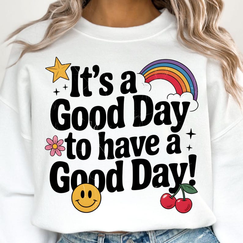 K&ouml;nnte beinhalten: Wei&szlig;er Pullover mit einem schwarzen Aufdruck, der "It's a Good Day to have a Good Day!" lautet. Der Aufdruck enth&auml;lt auch einen Regenbogen, einen Stern, eine Blume, ein Smiley und zwei Kirschen.